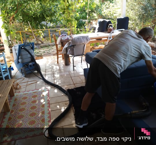 אדם מנקה ספה עם מכונת ניקוי ושואב אבק